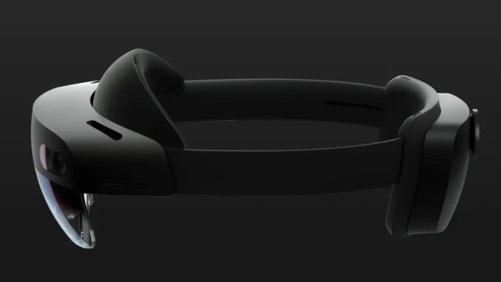 HoloLens 2 pokazany z boku na ciemnym tle: czarna opaska na głowę, przezroczysta osłona z przodu i tylna część urządzenia. Nikt nie ma go na głowie.