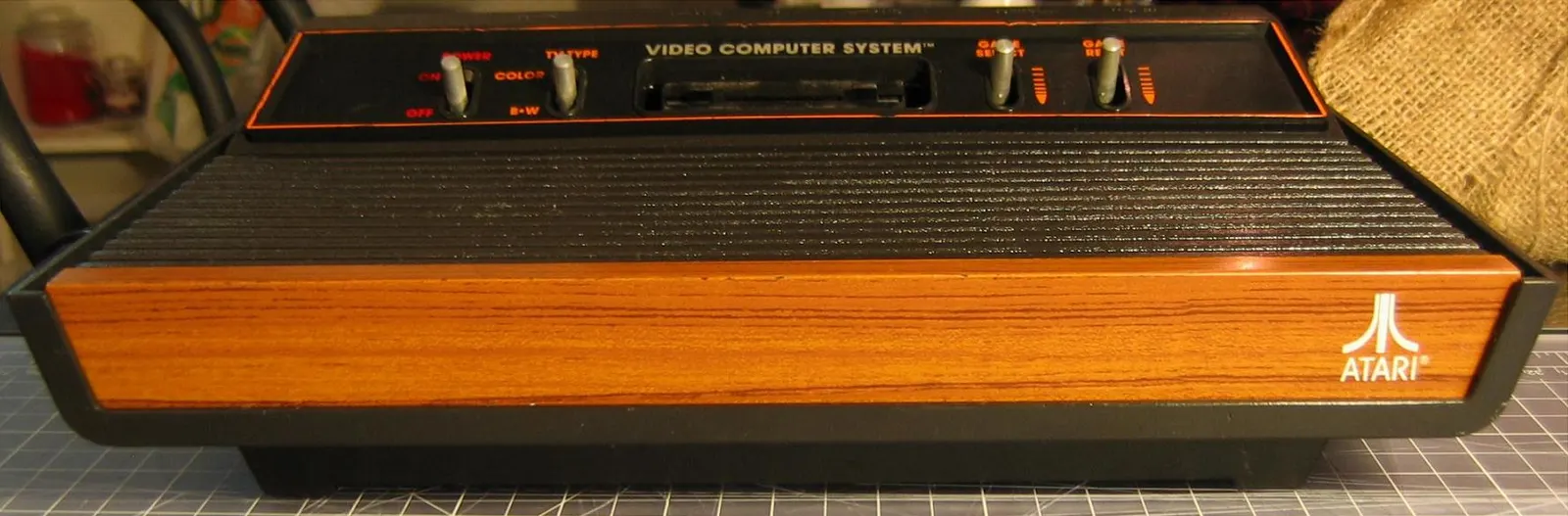 Atari VCS z drewnopodobnym frontem, przełącznikami i gniazdem kartridża.
